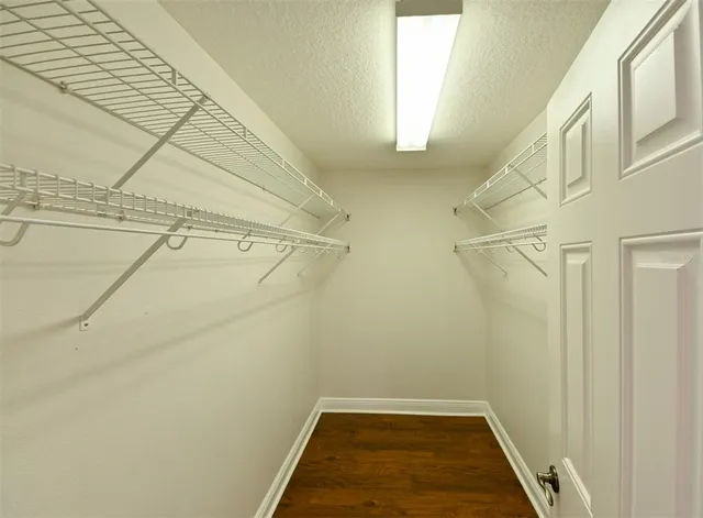 an empty room with wooden floor ceiling fan and windows