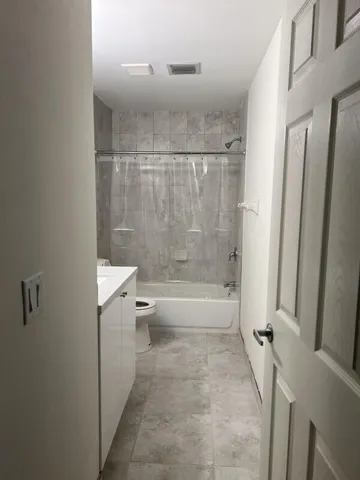 a bathroom with a granite countertop bathtub shower and toilet