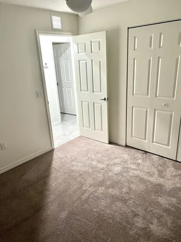 a view of an empty room and chandelier fan