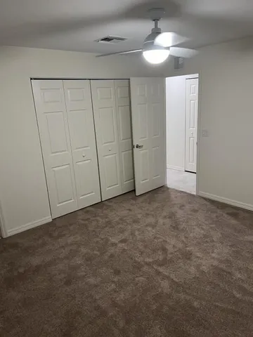 an empty room with a fan & a window