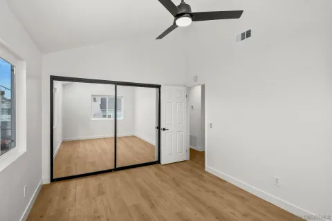 a view of empty room with wooden floor and fan
