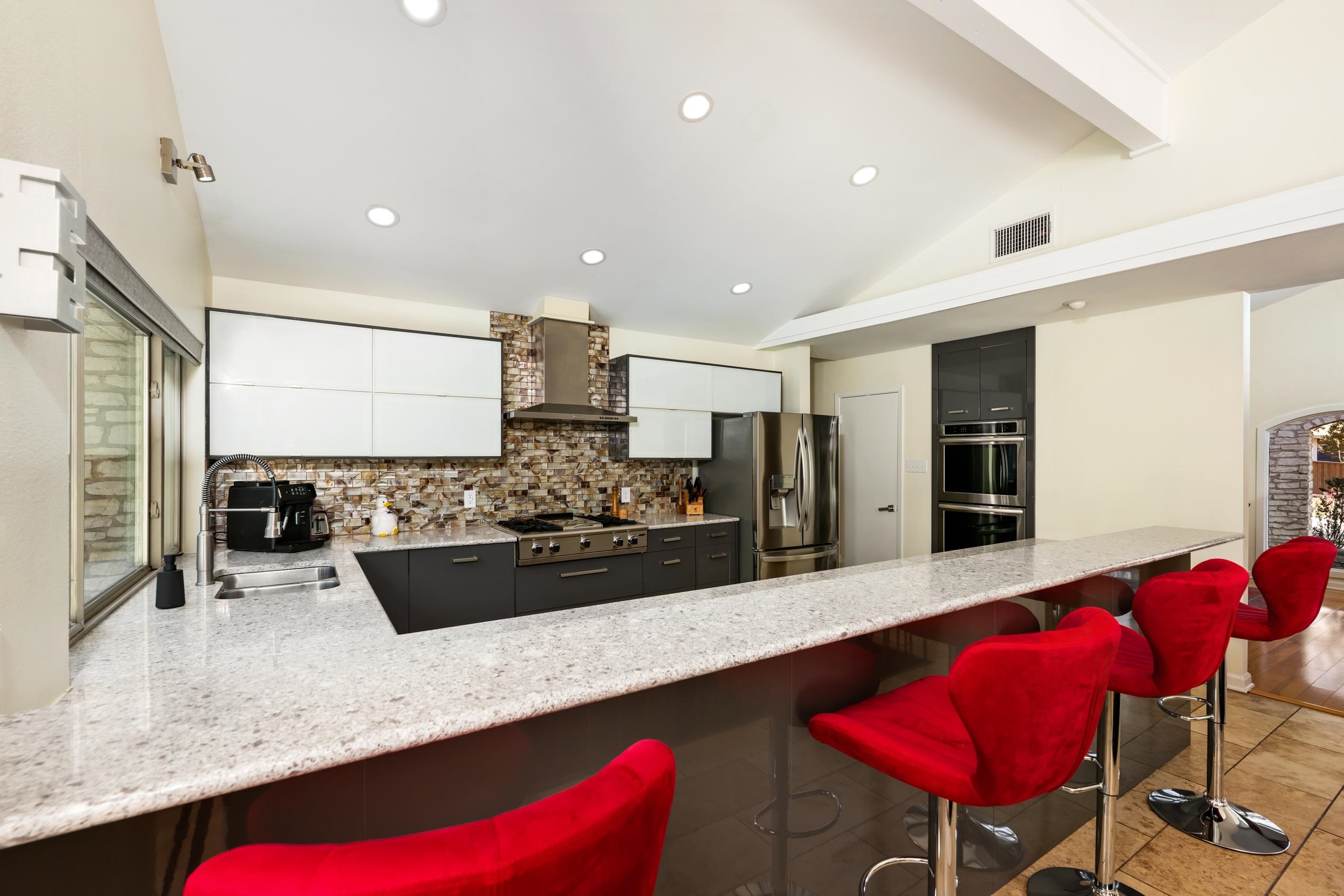 8805 Mountain Ridge Drive Austin, TX 78759 - Photo 8 of 30 a kitchen with stainless steel appliances kitchen island granite countertop a table chairs in it and wooden floors
