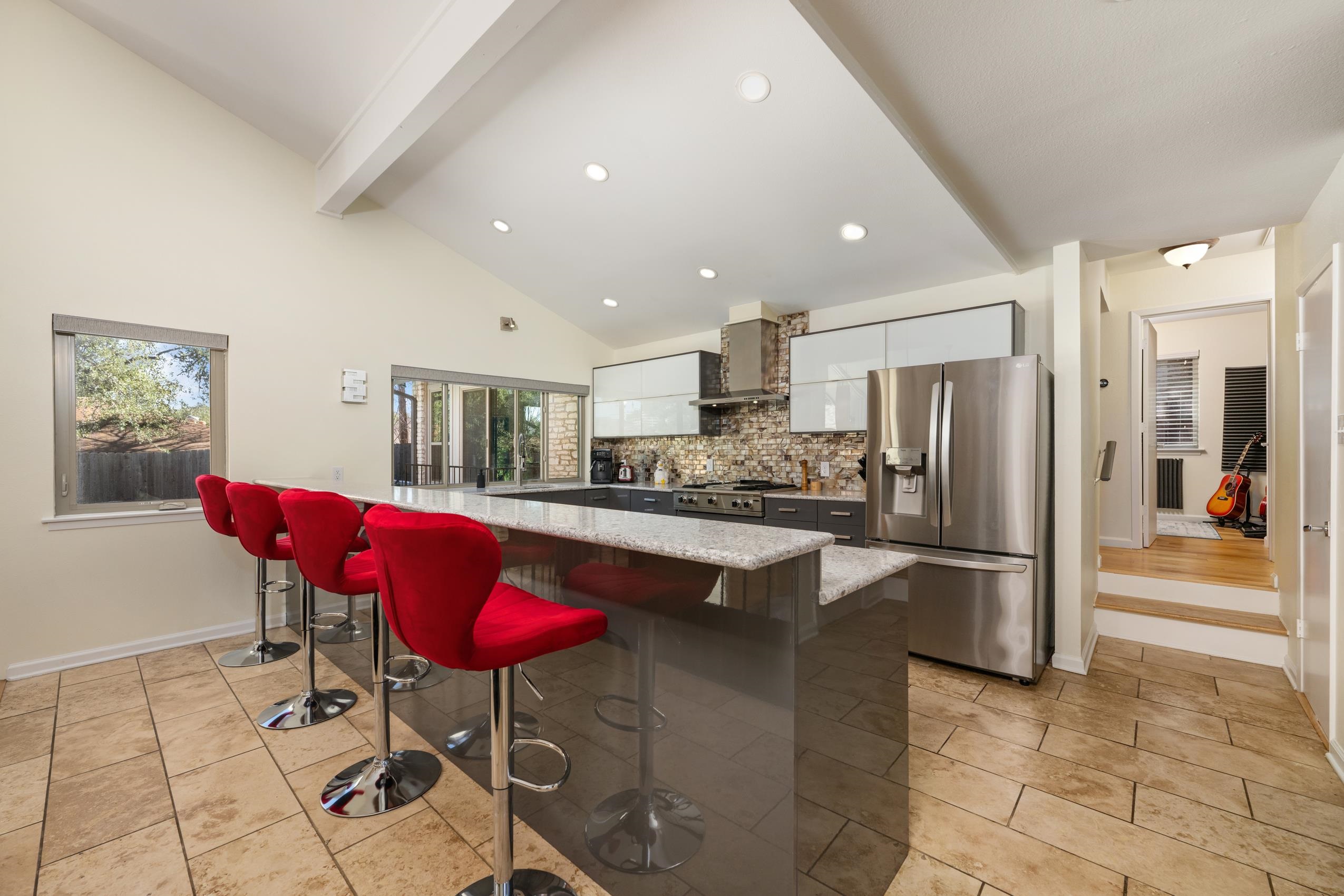 8805 Mountain Ridge Drive Austin, TX 78759 - Photo 9 of 30 a kitchen with stainless steel appliances kitchen island granite countertop a refrigerator a stove a dining table and chairs