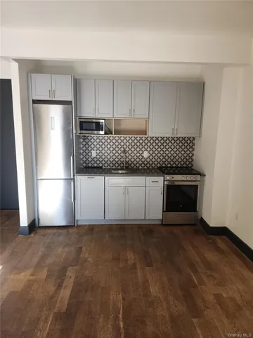 a kitchen with granite countertop a refrigerator a stove and cabinets