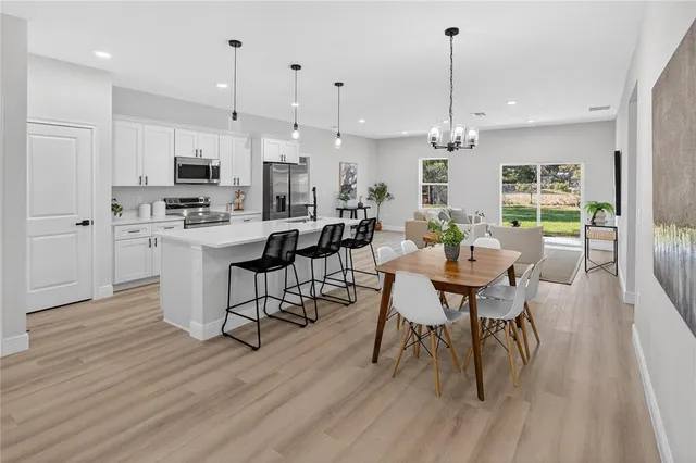 a view of a dining room and livingroom with furniture wooden floor kitchen chandelier