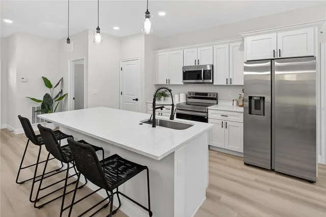 a kitchen with stainless steel appliances a table chairs microwave and refrigerator