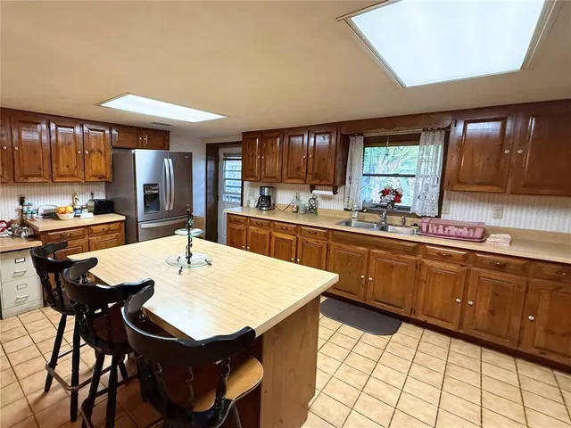 a kitchen with stainless steel appliances kitchen island granite countertop a sink a stove a table and chairs
