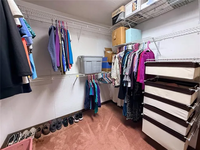 a view of walk in closet with clothes and shoes