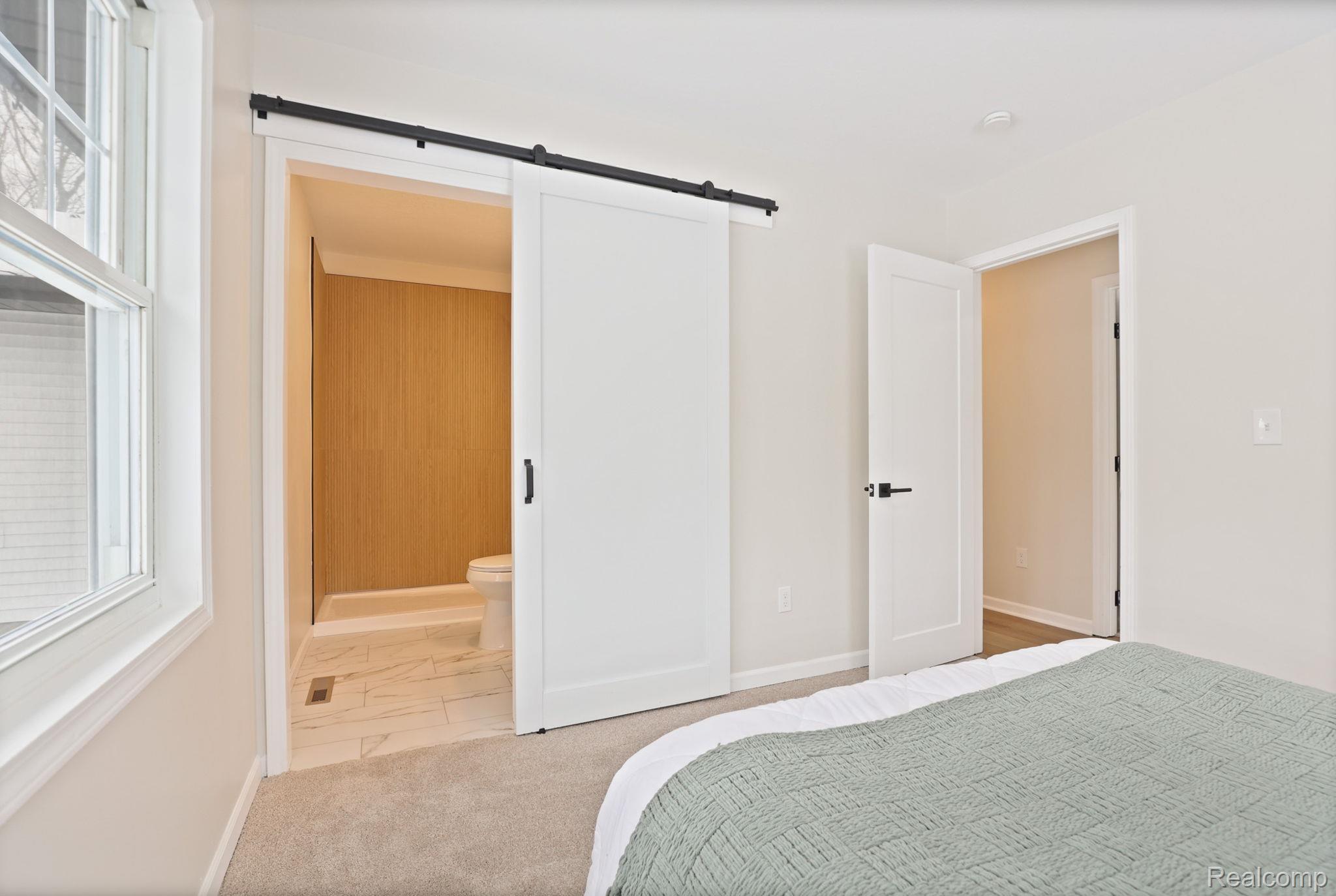 3937 Curtis Road Birch Run, MI 48415 - Photo 18 of 33 Bedroom with a barn door, ensuite bathroom, and light marble finish floors