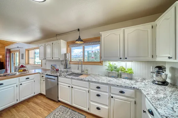 a kitchen with granite countertop white cabinets sink and stainless steel appliances
