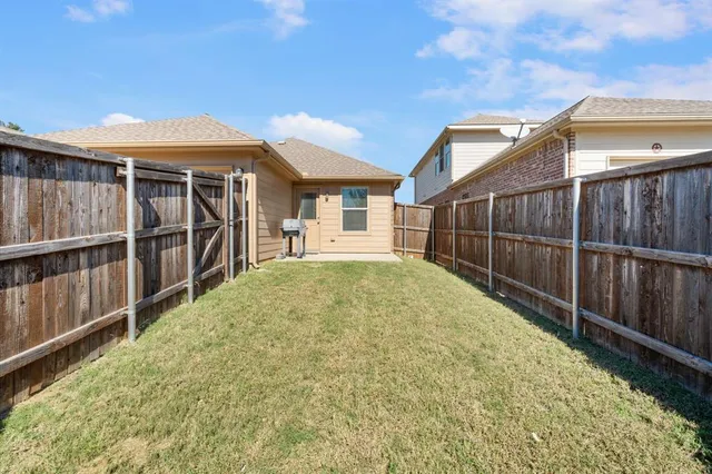 a view of backyard with large trees and wooden fence