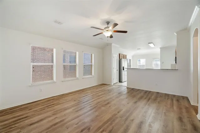 a view of an empty room with a kitchen and wooden floor