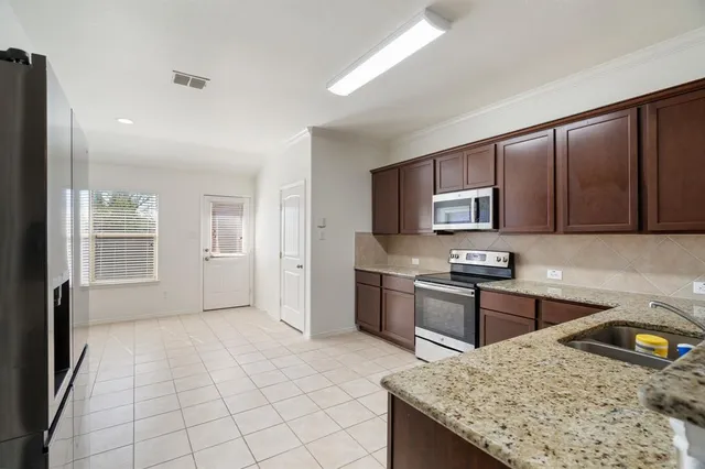 a kitchen with stainless steel appliances granite countertop a sink stove microwave and refrigerator