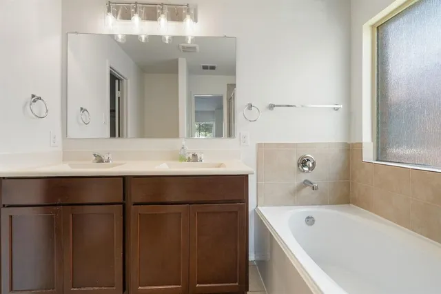a bathroom with a tub sink and mirror