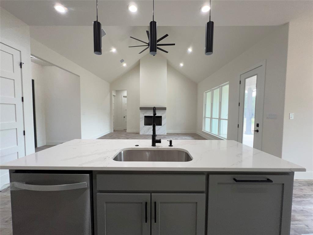 121 Cartwright Park Road Weatherford, TX 76087 - Photo 5 of 17 Kitchen island featuring a stainless steel sink, black faucet, and light-toned countertop