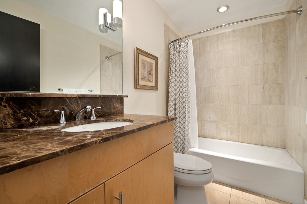 101 Broad Street, Unit 5D Boston, MA 02110 - Photo 7 of 13 a bathroom with a granite countertop sink toilet and shower