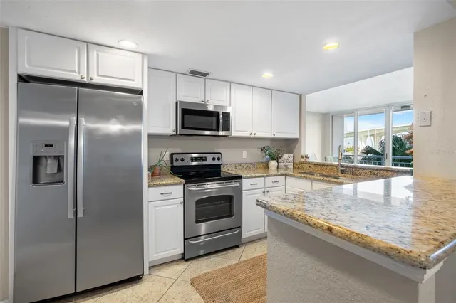 a kitchen with stainless steel appliances granite countertop a refrigerator a stove a sink and a microwave