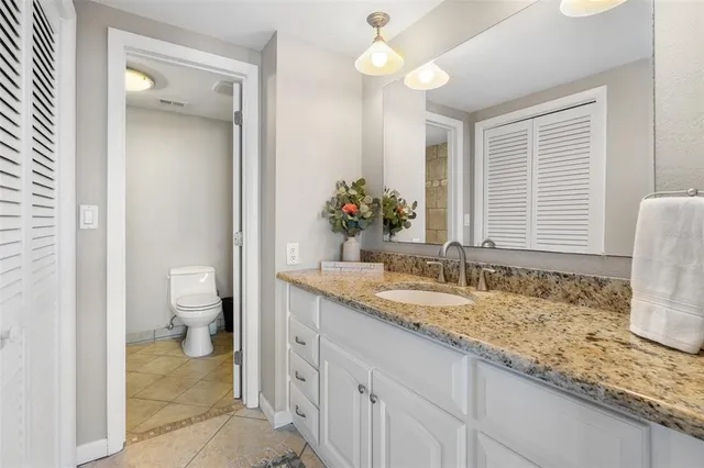 a bathroom with a granite countertop sink a toilet and a mirror
