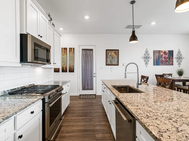 a kitchen with stainless steel appliances granite countertop a kitchen island a stove and a sink