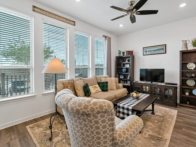 a living room with furniture a flat screen tv and a large window