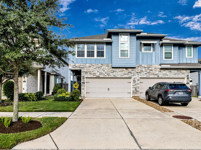 a view of a car parked in front of a brick house with plants