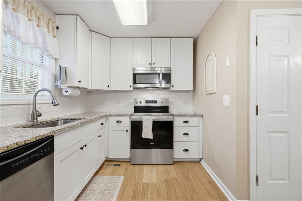 2525 Henderson Mountain Road Jasper, GA 30143 - Photo 9 of 23 a kitchen with stainless steel appliances granite countertop a stove and white cabinets