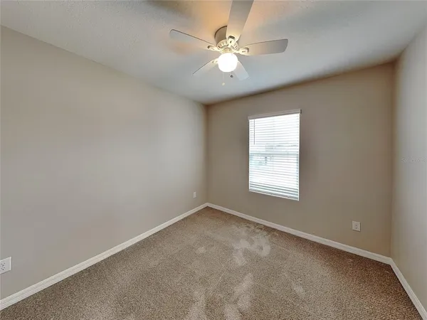 an empty room with windows and ceiling fan