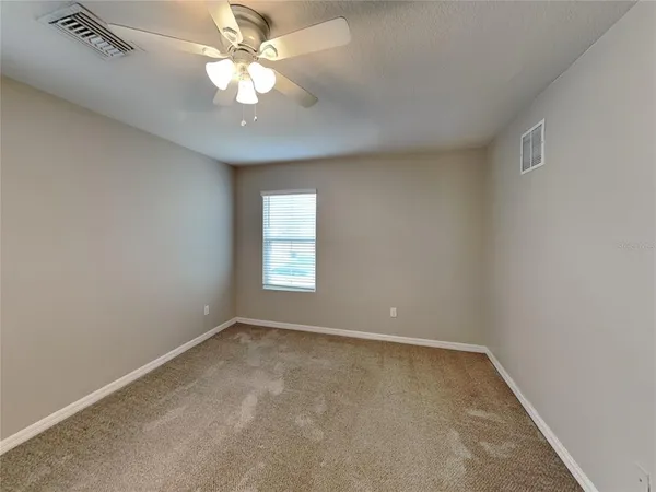 an empty room with a chandelier fan and windows