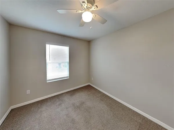 an empty room with a window and a fan