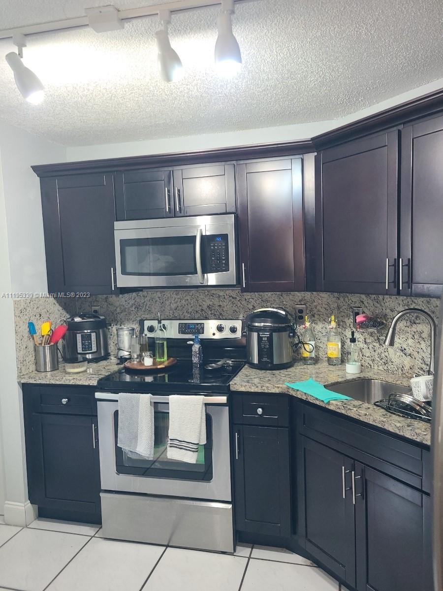10030 Hammocks Boulevard, Unit 101 Miami, FL 33196 - Photo 16 of 27 a kitchen with granite countertop stainless steel appliances stove microwave and sink