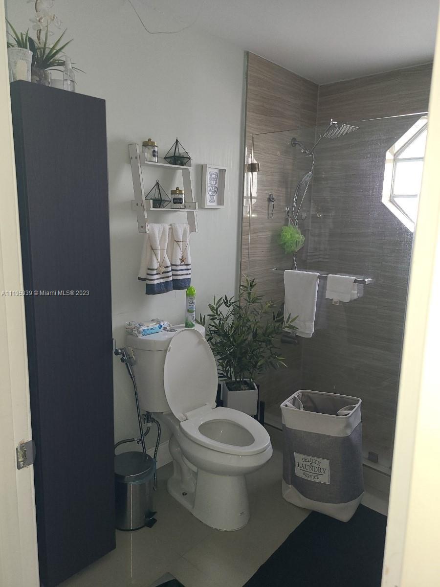 10030 Hammocks Boulevard, Unit 101 Miami, FL 33196 - Photo 20 of 27 a white toilet sitting next to a bathroom sink and a mirror