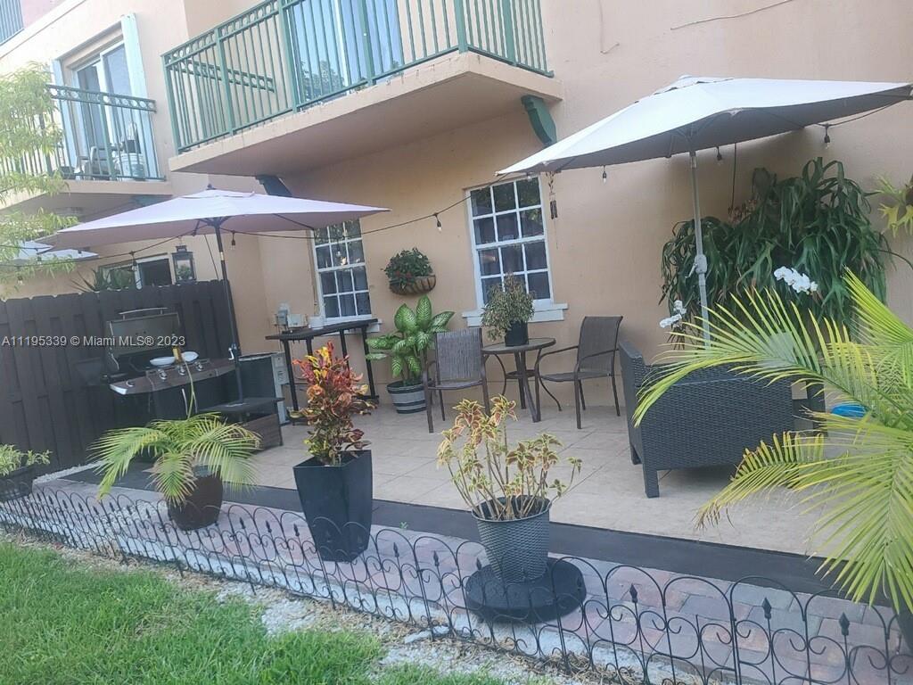 10030 Hammocks Boulevard, Unit 101 Miami, FL 33196 - Photo 8 of 27 a view of a patio with table and chairs potted plants