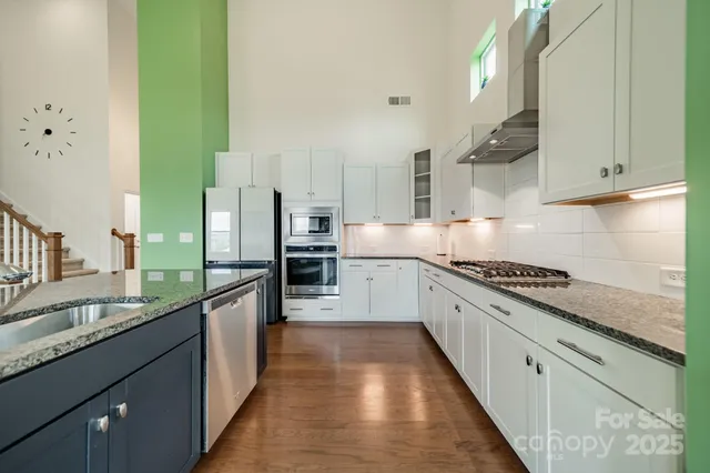 a large kitchen with stainless steel appliances granite countertop a lot of counter space and a sink