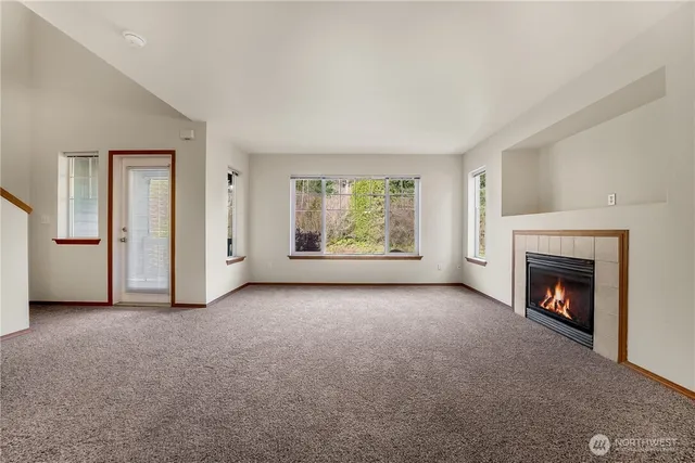 an empty room with windows fire place and fireplace