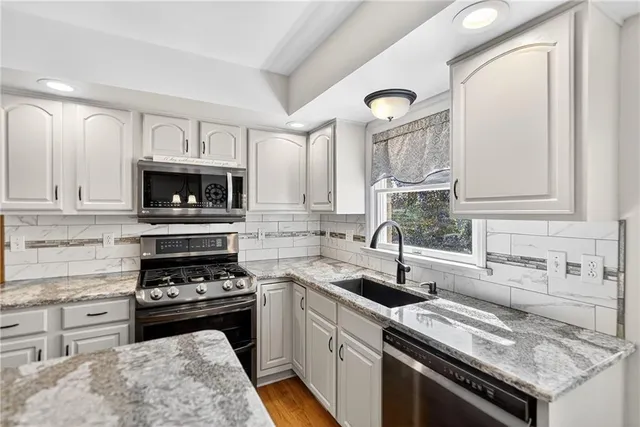 a kitchen with granite countertop a sink stainless steel appliances and cabinets