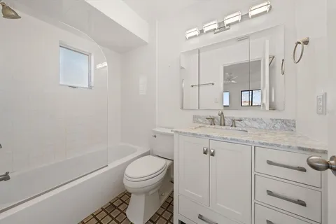 a bathroom with a granite countertop sink toilet a mirror and shower