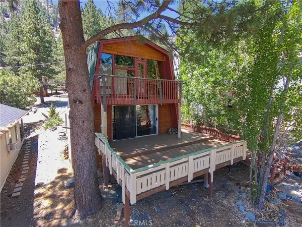 a view of a wooden house with a small yard and large trees