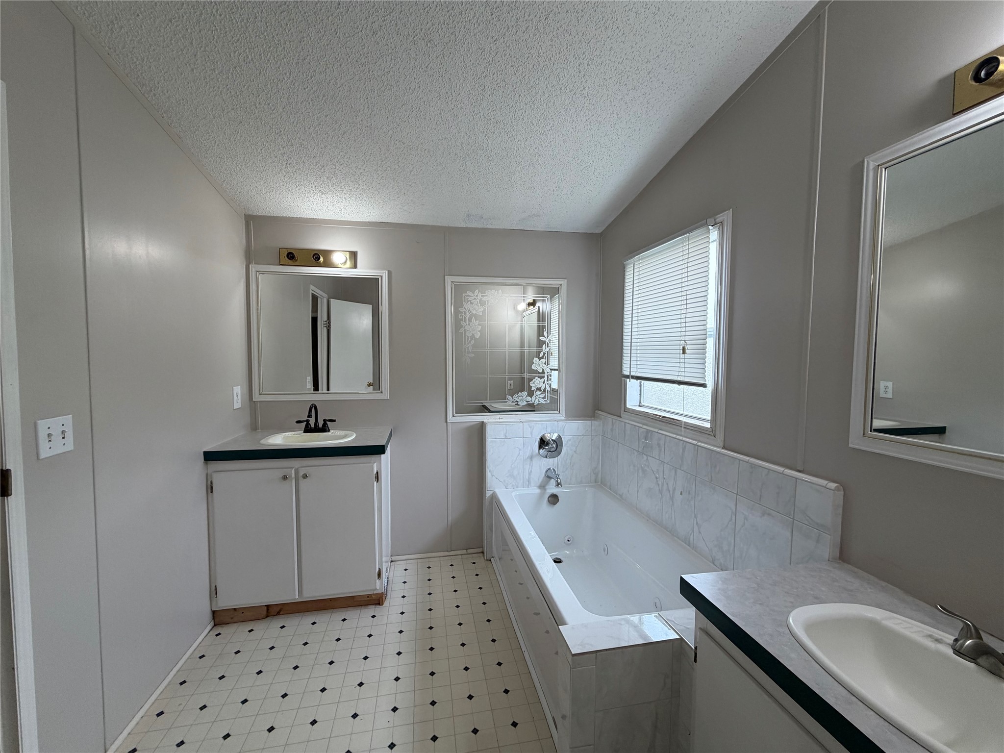 12609 Dessau Road, Unit 410 Austin, TX 78754 - Photo 9 of 11 Dual vanity sinks, a jetted bathtub, and tile accents