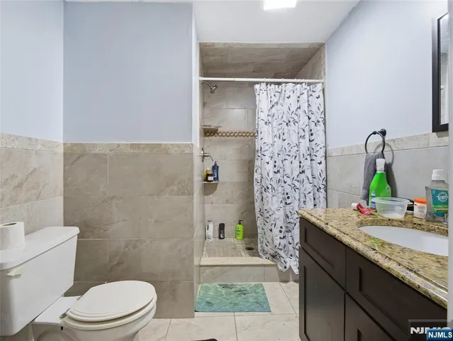 a bathroom with a granite countertop sink a toilet and shower