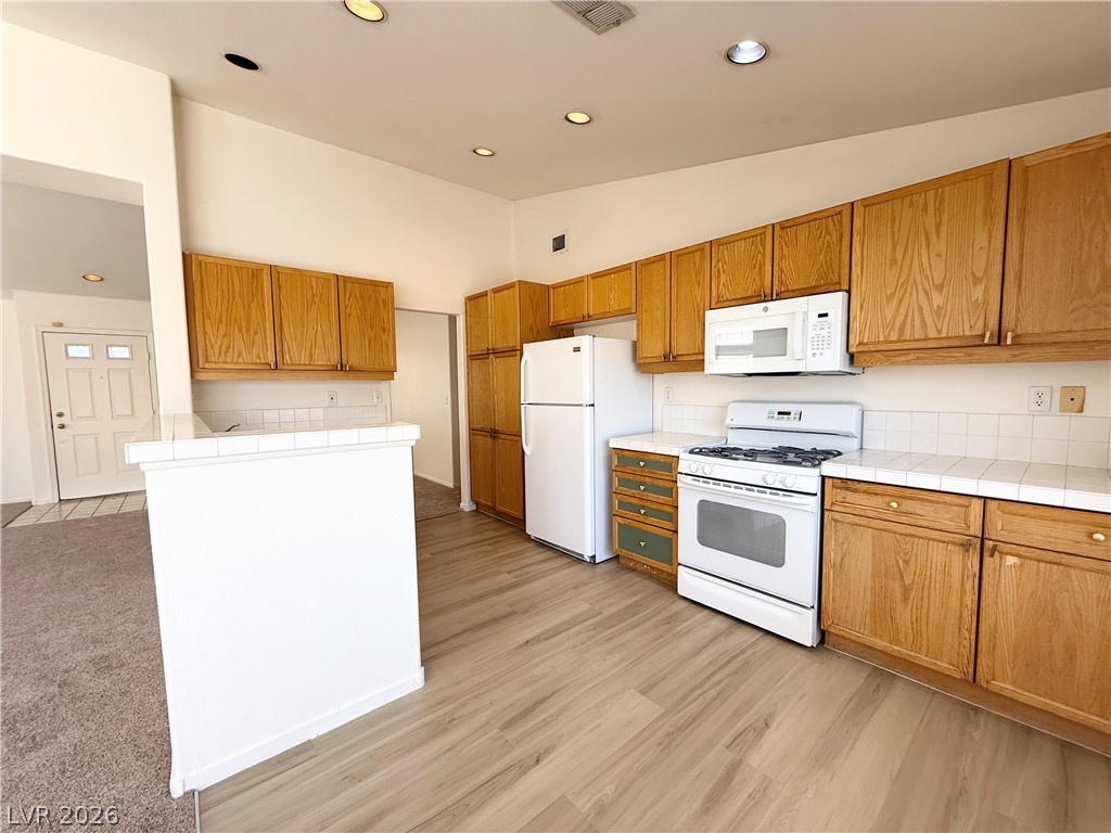 8870 Haviland Road Las Vegas, NV 89123 - Photo 4 of 22 A functional kitchen features wood cabinetry, white tile counters, and integrated appliances.