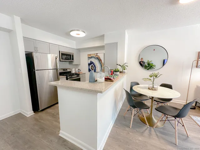 a room with a table chairs a refrigerator and a sink