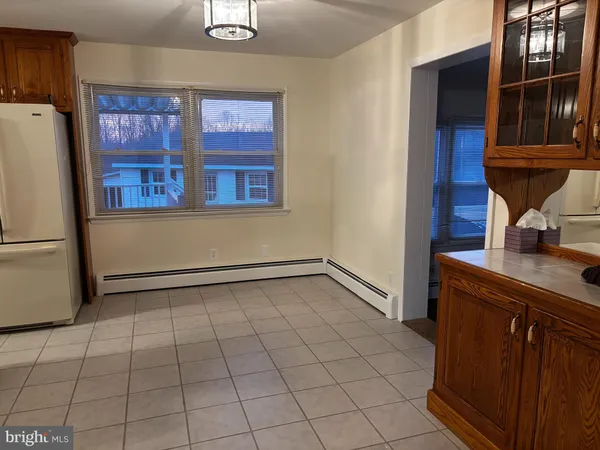 a view of a refrigerator in kitchen and an empty room