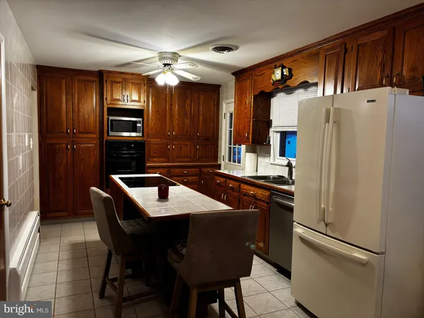 a kitchen with stainless steel appliances granite countertop a refrigerator a sink dishwasher a stove with chairs and island