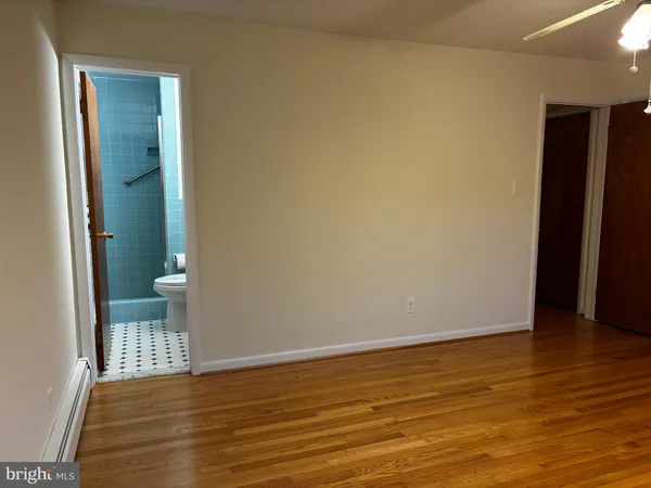 a view of an empty room with wooden floor and a bathroom