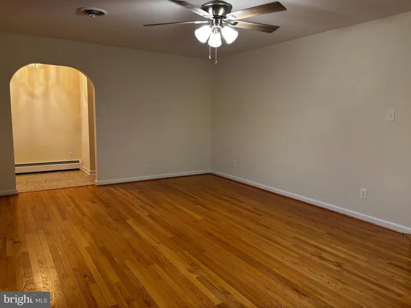 an empty room with wooden floor closet and fan