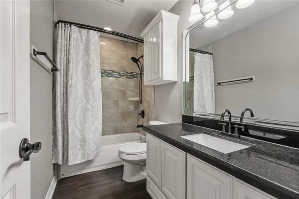 a bathroom with a granite countertop sink a toilet a mirror and shower