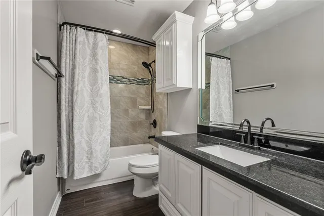 a bathroom with a granite countertop sink a toilet a mirror and shower