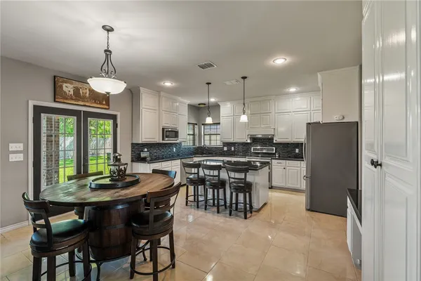 a kitchen with a dining table chairs stainless steel appliances and cabinets