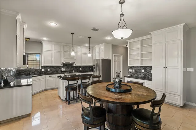 a kitchen with stainless steel appliances a dining table chairs and stove top oven