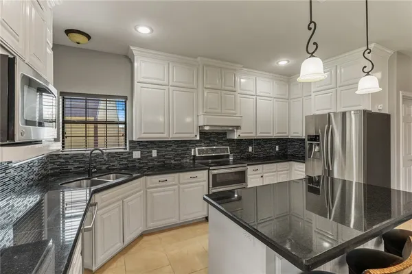 a kitchen with stainless steel appliances granite countertop a sink a stove and refrigerator